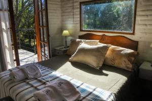um quarto com uma cama com almofadas e uma janela em El Rodeo Apart Cabañas em Santa Rosa de Calamuchita