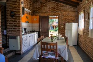 cocina con mesa y nevera blanca en El Rodeo Apart Cabañas en Santa Rosa de Calamuchita