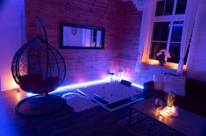 ein Wohnzimmer mit einer Badewanne in einem Raum mit lila Lichtern in der Unterkunft Apartament MINUS in Mrągowo