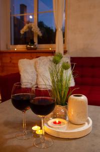 two glasses of wine and a candle on a table at Apartament MINUS in Mrągowo