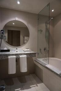 a bathroom with a tub, sink and mirror at Chapmans Peak Beach Hotel in Hout Bay