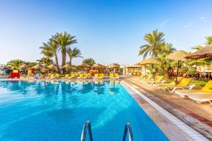 a pool at a resort with chairs and palm trees at TUI MAGIC LIFE Penelope Beach - Families & Couples in Midoun
