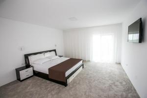 a bedroom with a large bed and a television at Vila Kalliopi in Eforie Nord