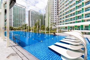 a large swimming pool with white chairs and buildings at Sabrina'sCrib Apartment 2BR by Azure Residences Near Manila International Airport in Manila