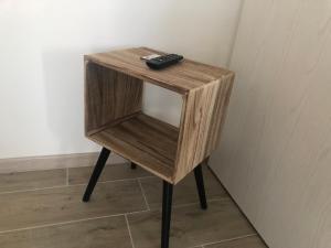 a small wooden side table with a remote control on it at Sole&Luna - Rooms in Eraclea