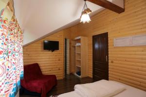 a room with a bed and a chair and a tv at Cabana Todireni Vatra Dornei in Vatra Dornei
