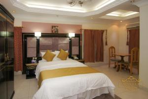 een slaapkamer met een groot bed en een bureau bij ALSAHRA Belshamal Hotel in Rafha