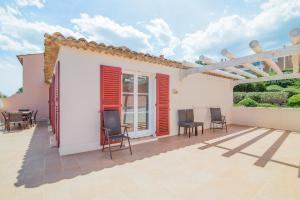 une terrasse avec volets rouges sur une maison blanche dans l'établissement Résidence Pierre & Vacances Les Restanques du Golfe de Saint-Tropez, à Grimaud