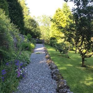 a gravel path in a garden with trees and flowers at Mews Cottage Ardoch Lodge Strathyre in Strathyre