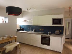 a kitchen with white cabinets and a sink and a table at Mews Cottage Ardoch Lodge Strathyre in Strathyre