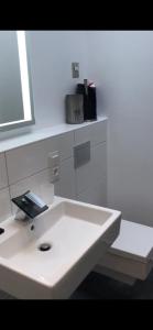 ein weißes Bad mit einem weißen Waschbecken und einem Fenster in der Unterkunft Alte Teestube Appartement 3 Penthouse in Norderney