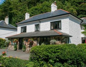 a white brick house with a black roof at Natal House Bed & Breakfast in Polperro
