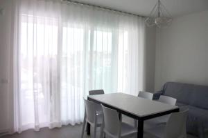 mesa de comedor con sillas blancas y ventana grande en West beach 3, en Lido di Jesolo
