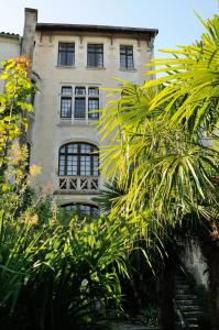 un bâtiment avec des fenêtres et des palmiers en face de celui-ci dans l'établissement Résidence du Château, à Jonzac