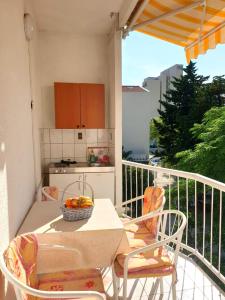 a balcony with a table with a bowl of fruit on it at Guest House Prskalo in Makarska