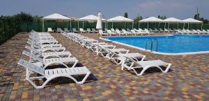 a row of white lounge chairs next to a swimming pool at Апартаменти перша лінія Затока Променад in Zatoka