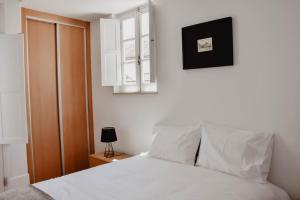 een slaapkamer met een wit bed en een raam bij Apartamento acolhedor e elegante em prédio típico - Self check in in Coimbra