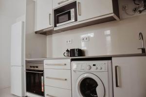 een keuken met een wasmachine en een magnetron bij Apartamento acolhedor e elegante em prédio típico - Self check in in Coimbra +31 foto's