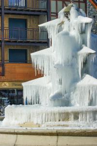 a ice covered fountain in front of a building at Hôtel Aurélia in Saint-Lary-Soulan