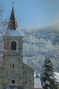 a stone church with a steeple with snow on it at Hôtel Aurélia in Saint-Lary-Soulan