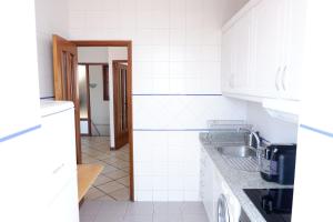 a kitchen with white tile walls and a sink at Kame House in Vila Nova de Gaia +11 photos