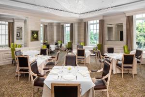 restauracja z białymi stołami, krzesłami i oknami w obiekcie Hotel Bennett Charleston w mieście Charleston