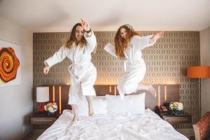 two girls jumping on a bed in a hotel room at Hotel Angeleno in Los Angeles