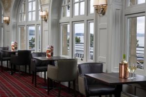 a restaurant with tables and chairs and windows at Argyll Hotel in Dunoon