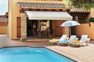 uma piscina com cadeiras e um guarda-sol ao lado de uma casa em Marisa em L'Escala