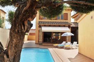 uma piscina em frente a uma casa com uma árvore em Marisa em L'Escala