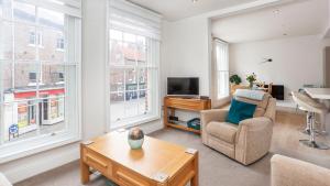 sala de estar con sofá, TV y ventanas en The King's- Gorgeous City Centre Apartment, en York