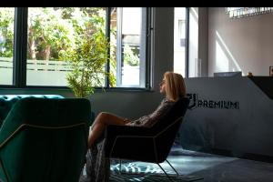 Hotel Premium في إسكوبية: امرأة تجلس على كرسي في غرفة