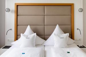 two beds with white pillows in a room at Hotel Freisicht in Hagnau