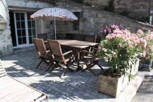 una mesa de madera y sillas con sombrilla y flores en Grand gîte Ardèche L'Avventura, en Grospierres