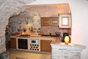 una cocina con armarios de madera y una pared de piedra. en Grand gîte Ardèche L'Avventura, en Grospierres 4 fotos más