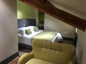 a bedroom with a bed and a yellow chair at Plasglasgwm in Betws-y-coed
