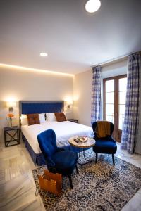 um quarto de hotel com uma cama e duas cadeiras e uma mesa em Plazuela del Carbón Suites em Cádis