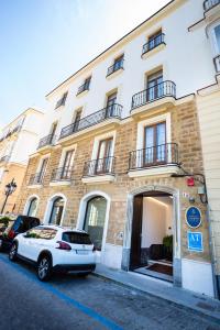 een witte auto geparkeerd voor een gebouw bij Plazuela del Carbón Suites in Cádiz