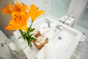 a bathroom sink with a vase with a yellow flower at Plazuela del Carbón Suites in Cádiz