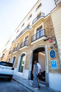 two people walking out of a building at Plazuela del Carbón Suites in Cádiz