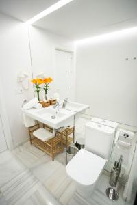 a white bathroom with a toilet and a sink at Plazuela del Carbón Suites in Cádiz