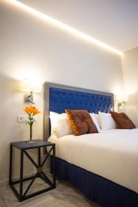 a bedroom with a bed with a blue headboard and a table at Plazuela del Carbón Suites in Cádiz