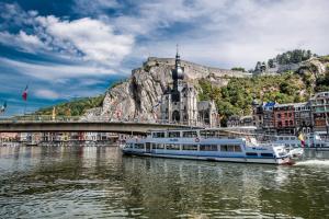 a boat in a river in front of a mountain at Hotel Aquatel in Dinant
