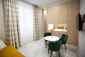 a living room with a table and chairs and a kitchen at Plazuela del Carbón Suites in Cádiz