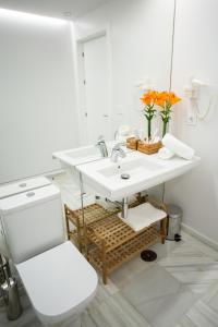 a white bathroom with a sink and a mirror at Plazuela del Carbón Suites in Cádiz