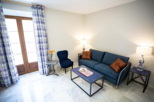 a living room with a blue couch and two chairs at Plazuela del Carbón Suites in Cádiz