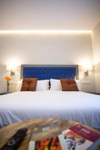 a bedroom with a large white bed and a table at Plazuela del Carbón Suites in Cádiz