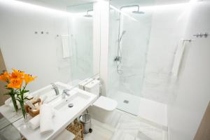 a white bathroom with a shower and a sink at Plazuela del Carbón Suites in Cádiz