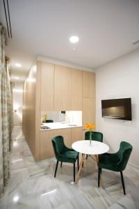 a dining room with a table and chairs and a kitchen at Plazuela del Carbón Suites in Cádiz