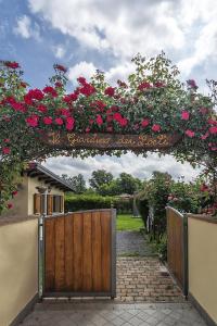 una cerca con una puerta con un cartel con rosas en B&B Il Giardino dei Poeti and Apartaments, en Lucca